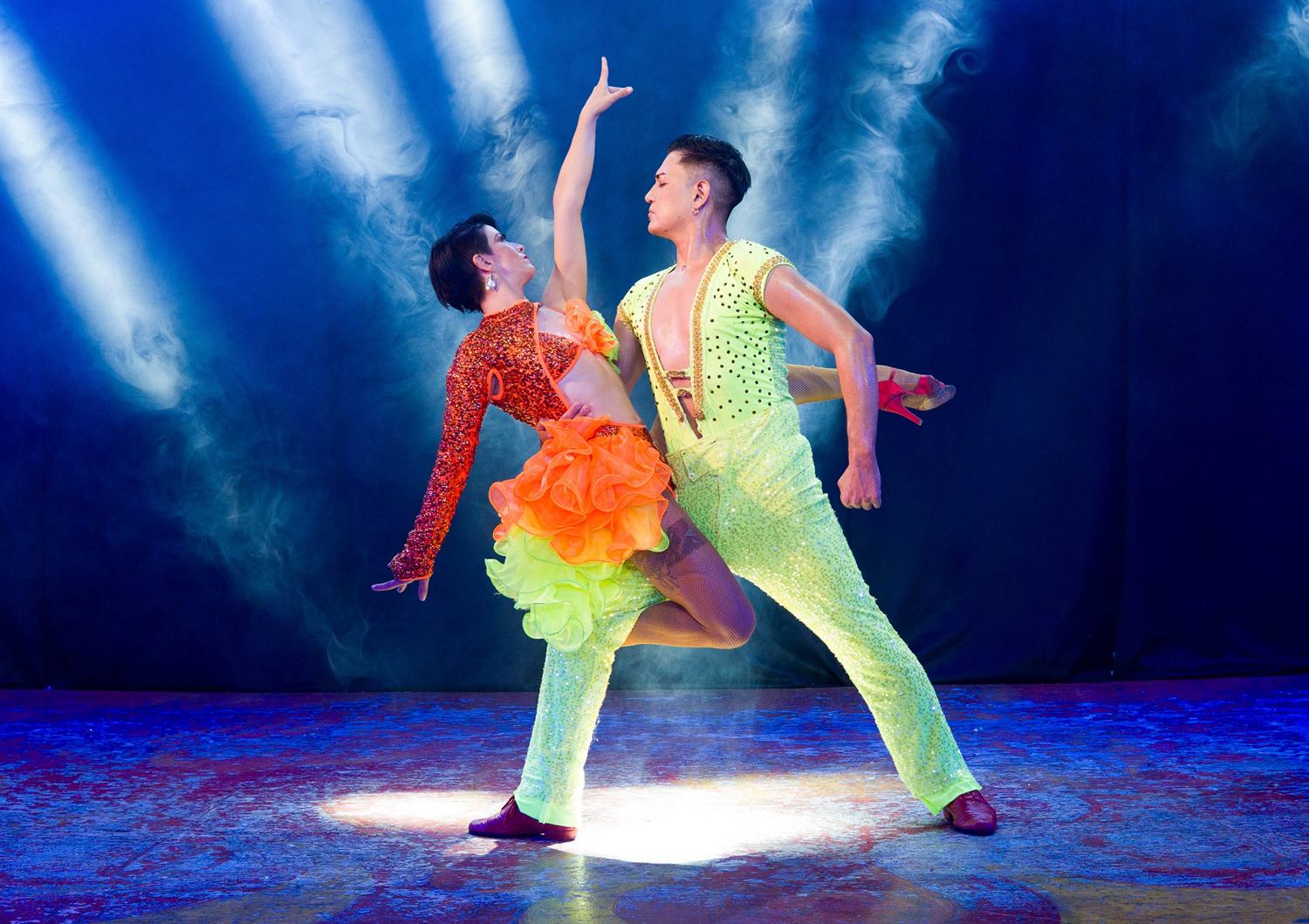 A couple in neon lime and orange held mid-turn